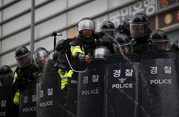 Riot policemen on the top of their bus use pepper spray to disperse protesters during an anti-government rally in central Seoul, South Korea, November 14, 2015. Tens of thousands protested against South Korean President Park Geun-hye's labour and education policies on Saturday in one of the largest street rallies in recent years, prompting police to use water canons and barricades to stop the crowd. REUTERS/Kim Hong-Ji